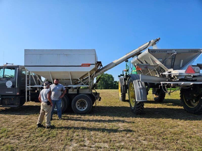 Personnel with farm equipment in the background